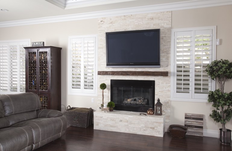 White plantation shutters in a Jacksonville living room with dark hardwood floors.